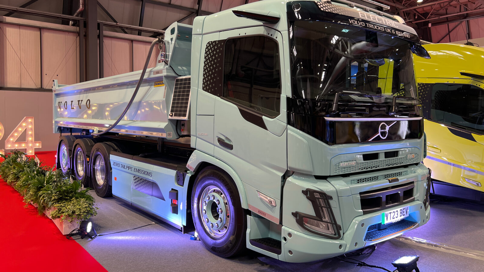 A Volvo electric truck in pale blue, looking modern and sleek bathed in spotlights on display at the NEC in Birmingham.