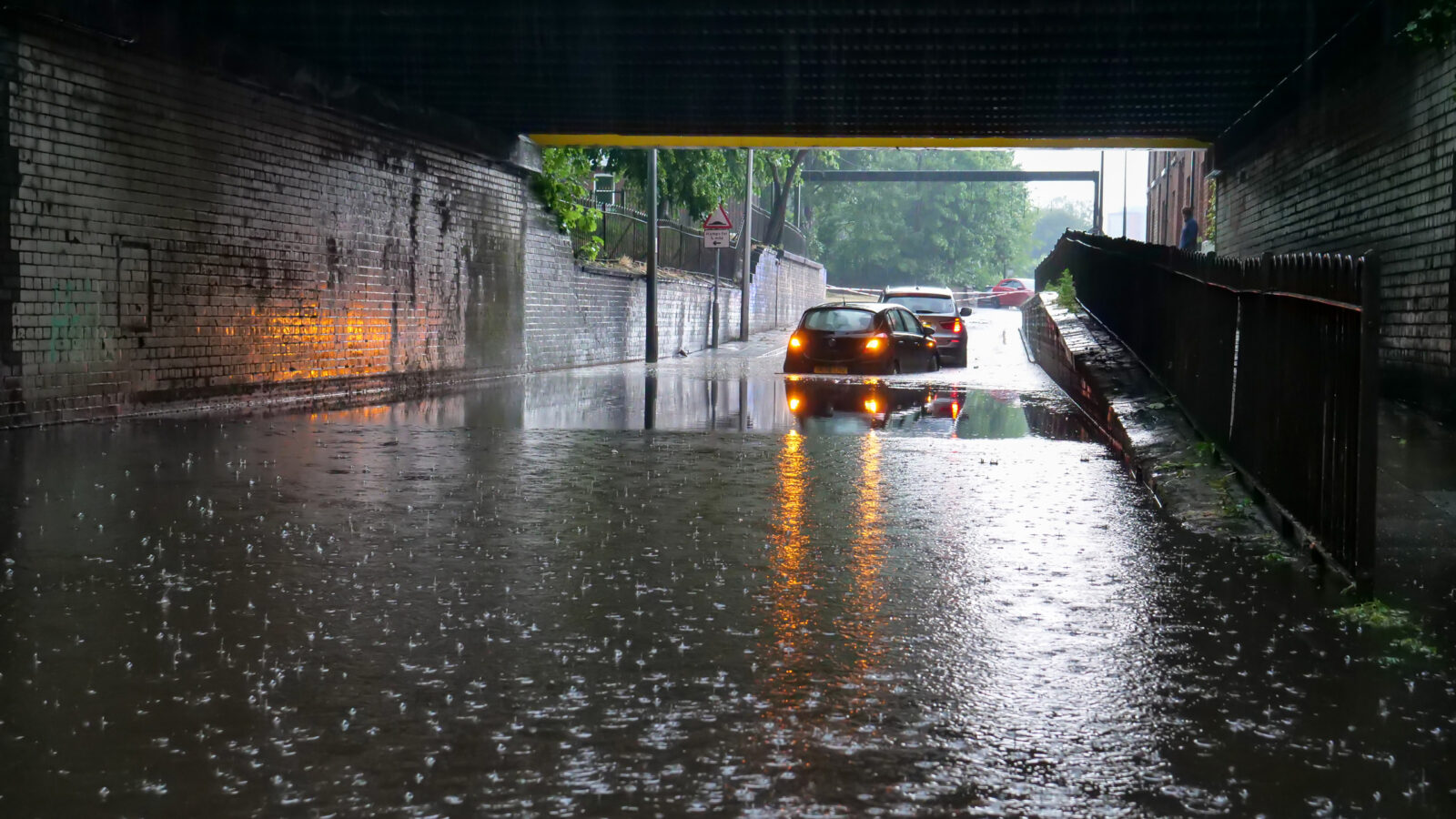 A flooded underpass with stranded vehicles.