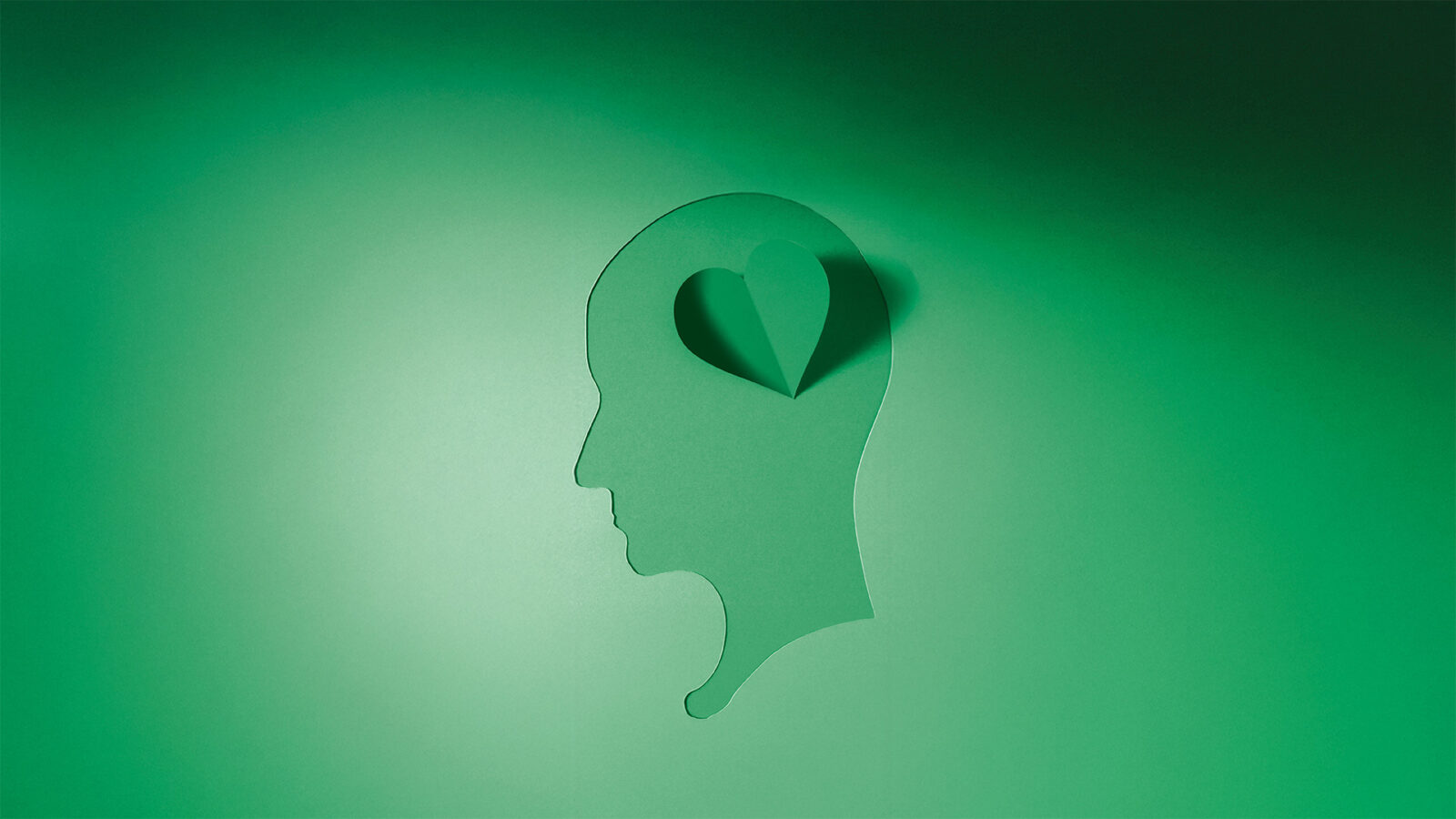 Paper silhouette of a head with an area cut out and folded to make a heart. Mental Health awareness Week 2025