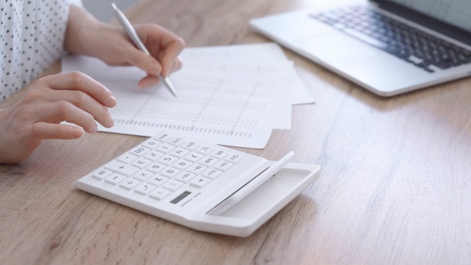 Office worker balancing budget with calculator and laptop on a desk. Bookkeeping, finance audit and taxes By volha_r