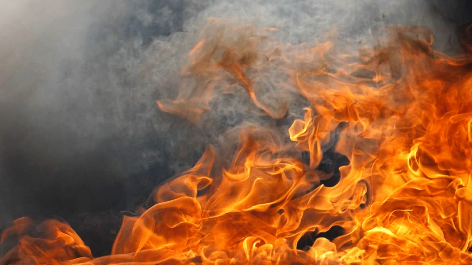 A raging flame of fire in slow motion with rich black smoke. Looks mesmerizing, can be used as a background in video editing